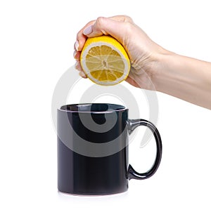 Hand squeezes out a lemon into black cup mug