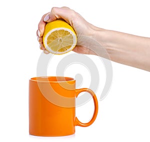 Hand squeezes out a lemon into orange cup mug