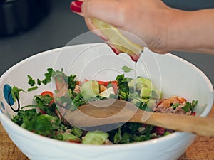 Hand squeezing lemon juice into a bowl of tuna salad.