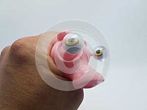 Hand squeezing a plastic pink pig with eyes bulging out