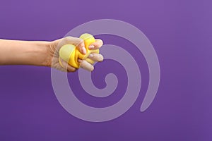 Hand squeezing stress ball on color background