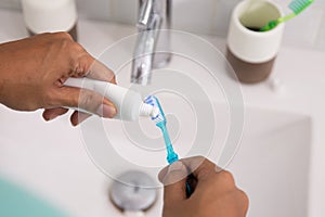 Hand squeezing tooth paste to the brush