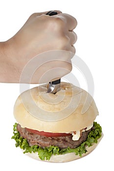 Hand stabbing a hamburger