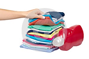 Hand with stack of clothes and detergent bottle, fresh laundry textile