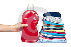 Hand with stack of clothes and detergent bottle, fresh laundry textile