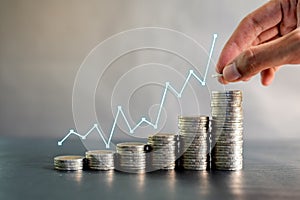 Hand stacking coins on black wooden table with profit line chart growth up. Business, finance, marketing, e-commerce concept and