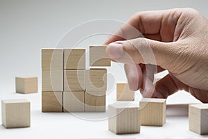 Hand stacking up wood cubes to build a complete 3x3 building