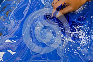 hand stirring blue ink in water