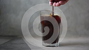 Hand stirring coffee with straw.