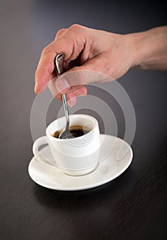 Hand Stirring Cup of Espresso Coffee with Spoon