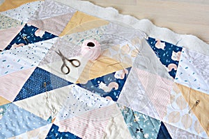 Hand stitch quilting process: pink cotton thread, needle and scissors