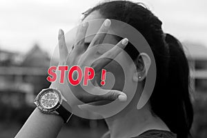 Hand stop gesture on young woman face in black and white. Stop warning concept.