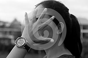 Hand stop gesture on young woman face with watch in hand in black and white background. No or stop gesture concept.