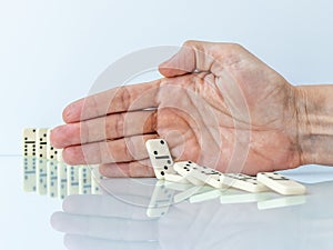 Hand stopping domino effect on white background.