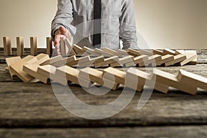 Hand stopping domino effect of wooden blocks photo
