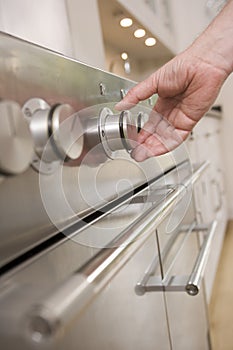 Hand on stove dial in kitchen