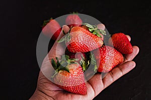 Hand strawberries in a black background photo