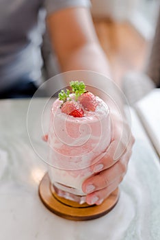 hand and strawberry milkshake on stone table, ingredient of strawberry, milk, ice and yogurt