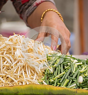 Hand of street vender preparing bean sprouts and scallion for Pa photo