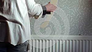 Hand stripping wallpaper from home internal wall close up