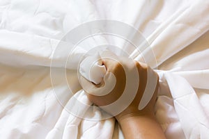 Hand strongly grasp white bed sheet