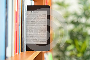 Hand of student keeping digital tablet in bookshelf in school library