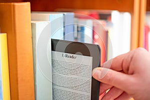 Hand of student keeping digital tablet in bookshelf in school library