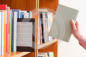 Hand of student keeping digital tablet in bookshelf in school library