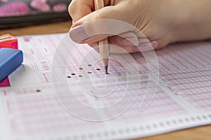 Hand student testing in exercise and taking fill in exam carbon paper computer sheet with pencil at school test room, education