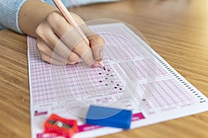 Hand student testing in exercise and taking fill in exam carbon paper computer sheet with pencil at school test room, education