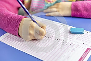 Hand student testing in exercise and taking fill in exam carbon paper computer sheet with pencil at school test room, education