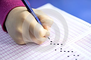 Hand student testing in exercise and taking fill in exam carbon paper computer sheet with pencil at school test room, education