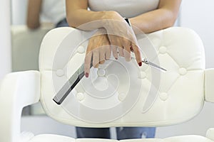 Hand of stylish young woman hairdresser, female hair stylist, modern barber girl holding professional scissors and comb