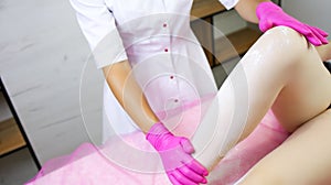 The hand of the sugar epilator, which also holds the client`s leg, already covered in powder, to retreat and work wit