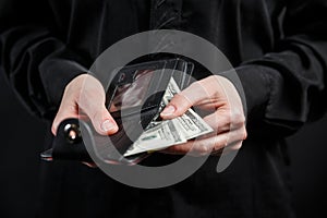 Hand in suit takes out dollar money from a wallet