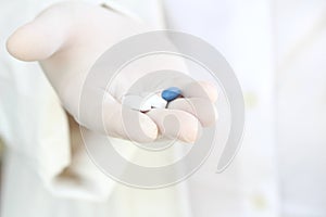 Hand in surgical glove holding pills