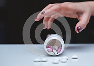 Hand surrounded by many pills.