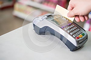 Hand swiping credit card on payment terminal in store