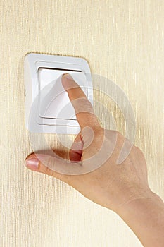 Hand switches on the lightswitch on the wall