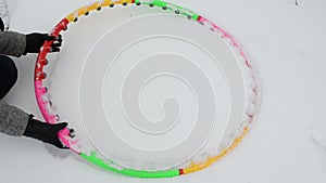 Hand take colorful sport fitness hoop waist from winter snow
