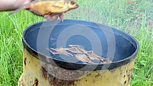 Hand take ecologic smoked fish meal from smokehouse rusty barrel