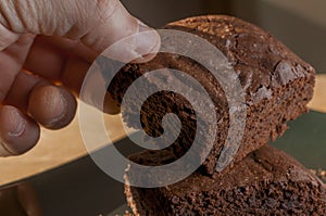 Hand take a slice of chocolate brownie from a plate