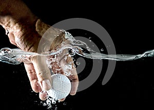 Hand take up Golf ball splashing in water