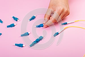 Hand takes blue LC optical attenuator on pink background