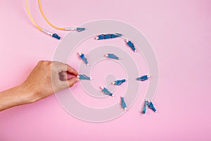 Hand takes blue LC optical attenuator on pink background