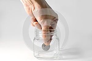 The hand takes the last coin from the piggy bank, close-up. Quarter dollar coin in a glass bottle, isolate on a white background.