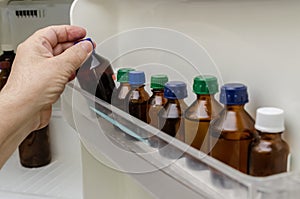 Hand takes medicine in amber bottle