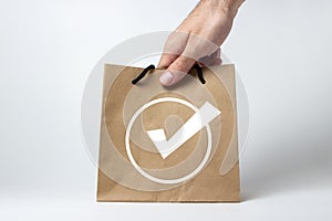 A hand takes a paper bag on a white background. Purchase and sale of goods via the Internet.
