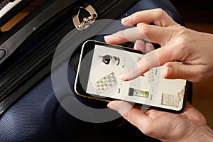 Hand takes phone and search medications on travel suitcase background, medical tourism concept, purchase and delivery of medicines