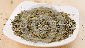 Hand takes sencha green tea dry leaves close up.